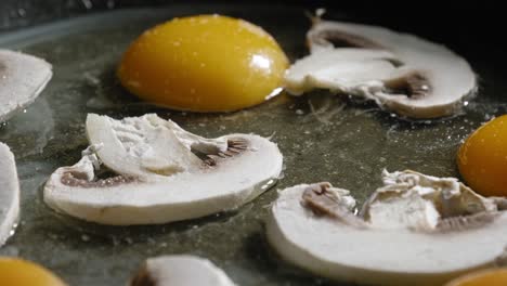 Macro-Shot-Of-Sliced-Champignon-Mushrooms-On-Eggs-In-A-Pan,-Sprinkled-With-Salt,-Cayenne,-And-Black-Pepper