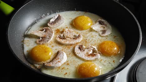Freír-Huevos-Con-Champiñones-En-Una-Sartén,-Sazonados-Con-Sal,-Pimienta-Y-Cayena-En-Polvo