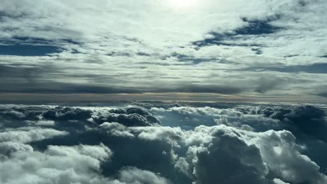 Cockpit-view-of-a-cloudy-sky-flying-between-layers-of-white,-black-and-grey-clouds-during-the-sunset