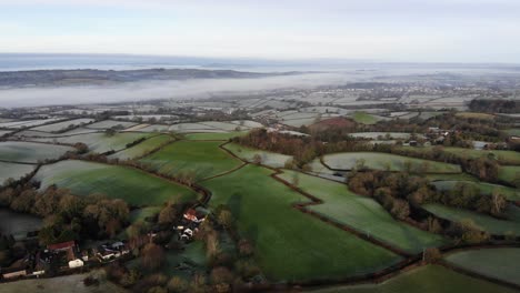 Aerial-backwards-shot-of-the-Otter-Valley-countryside-in-Devon-England-on-a-frosty-morning