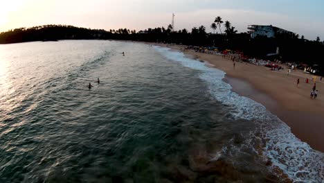Aerial-Drone-Over-Popular-And-Busy-Tourist-Beach-At-Sunset-In-Mirissa-Sri-Lanka-With-People-Swimming