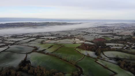 Aerial-panning-left-shot-of-Farmland-on-a-misty-frosty-morning-in-Devon-England