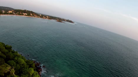 Aerial-Drone-Pans-Over-Island-Hillside-With-Trees-To-Deep-Blue-Expansive-Ocean-At-Sunset-In-Sri-Lanka