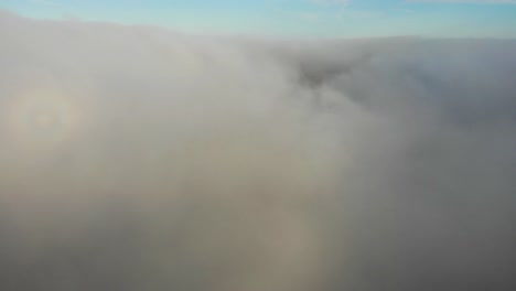 Aerial-shot-rising-up-and-through-the-clouds-to-reveal-a-blue-sky