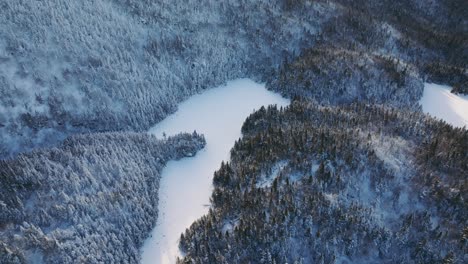 Vista-Panorámica-De-Las-Montañas-Del-Bosque-Con-Río-Congelado-Durante-El-Invierno-En-El-Este-De-Quebec,-Canadá