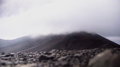 Zeitraffer-Von-Grauen,-Schweren-Wolken,-Die-Den-Gipfel-Der-Felsigen-Vulkanberge-Auf-Der-Kanarischen-Insel-Fuerteventura,-Spanien,-Bedecken