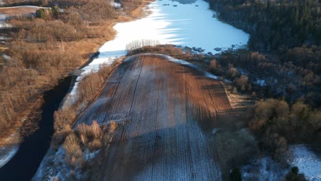 AERIAL:-Rows-of-Plowed-Earth-Covered-with-Snow-and-Frost-in-Early-Spring-Near-Frozen-Lake