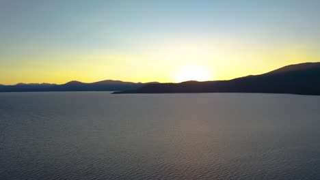 Sonnenaufgang-über-Dem-See-Mit-Bergsilhouette-Im-Hintergrund