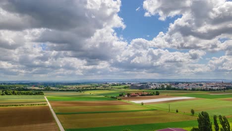 Aerial-hyperlapse-with-many-clouds-at-sunny-day-over-green-fields-in-4K