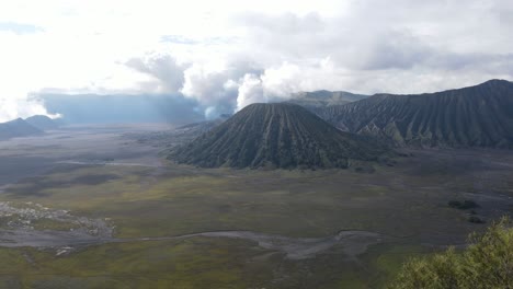 aerial-view,-in-the-morning-the-beautiful-Mount-Bromo-area-is-slightly-smoky-and-the-savanna-is-green