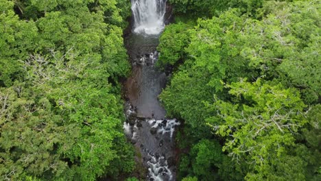 Aerial-shot-of-water-cascading-over-canyon-precipice-of-a-beautiful-Mexican-waterfall-surrounded-by-lush-green-vegetation