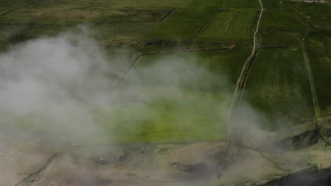 AERIAL---Green-fields-and-a-road,-Hvitserkur,Vatnsnes,-Iceland,-wide-shot-forward