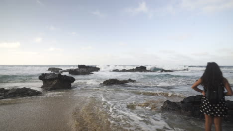 Junge-Touristische-Frau,-Die-Innerhalb-Des-Tropischen-Strandes-Des-Meerwassers-Mit-Felsformation-Auf-Der-Kanarischen-Insel-Fuerteventura-Spazieren-Geht