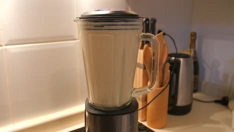 Blick-Auf-Hausgemachte-Hafer--Und-Milchmischung,-Die-In-Einem-Mixer-Hafermilch-In-Der-Küche-Mit-Weißen-Fliesen-Im-Hintergrund-Mahlt