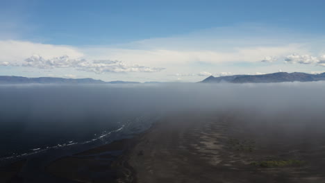 AERIAL---Blue-horizon-above-coastline,-Hvitserkur,Vatnsnes,-Iceland,-rising-above-fog