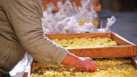 Older-Italian-Women-making-and-selling-handmade-traditional-orecchiette-pasta-in-the-street-markets-of-Bari-Italy,-Puglia,-moving-and-adjusting-the-drying-racks,-static-shot,-no-faces,-bright,-sunny