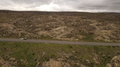Aerial-tracking-shot-of-car-on-highland-road-carrying-box-trailer-during-cloudy-day-in-Argentina