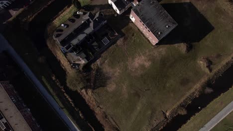 Top-down-aerial-approach-of-former-youth-prison-facility,-now-abandoned-waiting-for-demolition-and-refurbishment-of-the-moated-plot-field-in-a-residential-neighbourhood-of-Zutphen,-The-Netherlands
