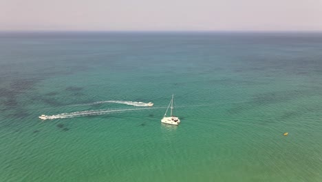 Aerial-shot-around-catamaran-in-turquoise-sea-with-other-boats-passing-by