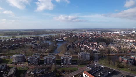 Backwards-aerial-movement-showing-residential-neighbourhoods-of-Zutphen-revealing-former-youth-prison-facility,-now-abandoned-waiting-for-demolition-and-refurbishment-of-the-moated-plot-field