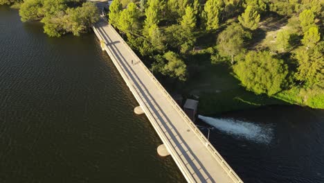 Vogelperspektive-Eines-Radfahrers-Auf-Dem-Fahrrad,-Der-Den-Fluss-Durch-Die-Dammbrücke-In-Der-Wildnis-Von-Argentinien-überquert