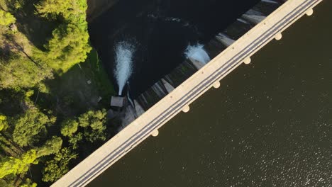 Aerial-flyover-large-Dam-and-passing-water-flowing-down-in-wilderness-during-sunset-time