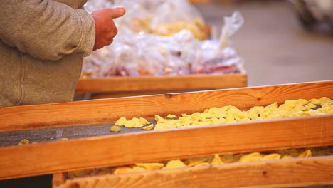 Older-Italian-Women-making-and-selling-handmade-traditional-orecchiette-pasta-in-the-street-markets-of-Bari-Italy,-Puglia,-static-shot,-no-faces,-bright,-warm-and-cozy