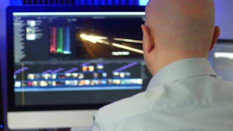 Over-shoulder-of-an-unrecognizable-man-working-as-video-editor-editing-on-a-computer