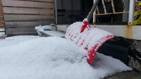 Sanfte-Schneeflocken-Fallen,-Während-Eine-Rote-Schaufel-Mit-Schwerem-Schnee-Bedeckt-Ist