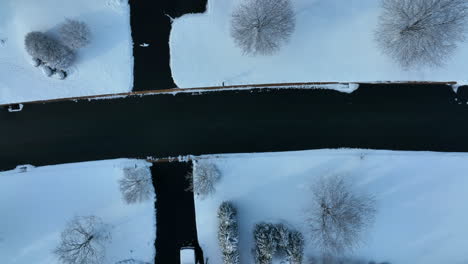 Top-down-aerial-of-street-road-and-landscaping-in-winter-snow-neighborhood