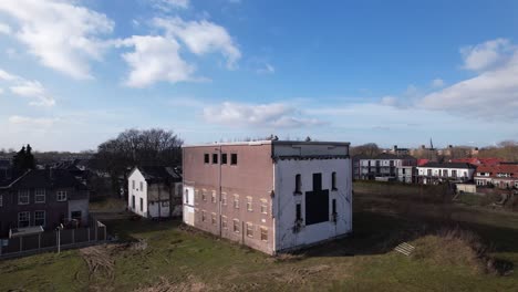 Backwards-aerial-reveal-showing-surrounding-of-former-youth-prison-facility,-now-abandoned-waiting-for-demolition-and-refurbishment-of-the-moated-plot-field-in-Zutphen,-The-Netherlands