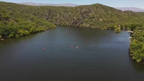 Aerial-drone-shot-showing-group-of-kayakers-in-the-middle-of-natural-lake-in-Cordoba,Argentina---Beautiful-nature-landscape-with-mountains-in-summer