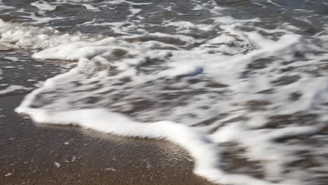Close-Up-on-Rolling-Waves-at-a-Sandy-Beach