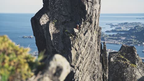 Person-trad-climbing-steep-cliff-near-seaside-of-Norway-Lofoten-region