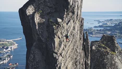 Powerful-person-trad-climbing-rocky-cliff-in-Norway-with-ocean-behind-it
