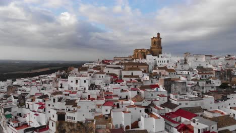 Forward-flying-aerial-towards-church-in-whitewashed-village-in-Andalusia,-Spain