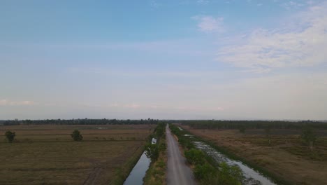 Aerial-footage-over-the-farm-road-as-it-goes-forward-and-then-ascends-revealing-a-lovely-landscape,-Pak-Pli,-Nakhon-Nayok,-Thailand