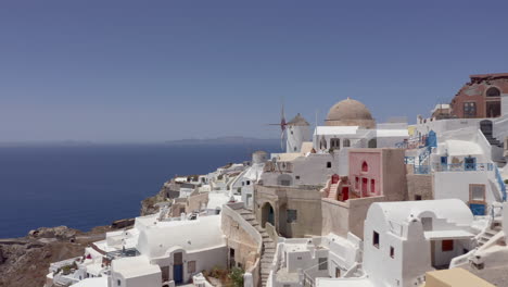 Aerial:-Drone-flies-at-low-altitude-in-Oia-of-Santorini,-Greece-close-to-the-windmills