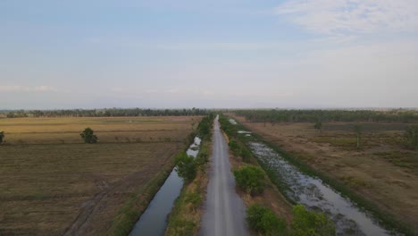 Ascending-aerial-footage-of-the-road-with-canals-in-Pak-Pli,-Nakhon-Nayok,-Thailand