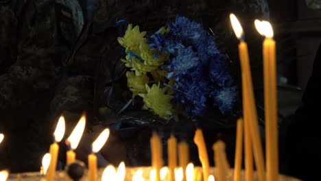 Ein-Soldat-Mit-Gelben-Und-Blauen-Blumen-Wird-Durch-Brennende-Gebetskerzen-Bei-Der-Beerdigung-Eines-Ukrainischen-Soldaten-Während-Der-Russischen-Invasion-Des-Landes-Gesehen