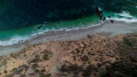 High-aerial-view-of-the-rocky-shoreline-at-Nerja,-moving-backwards-and-tilting-up