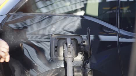 Man's-hands-removing-electrical-fuel-nozzle-of-pump-to-tank-electric-car---Cinematic-focus-blur