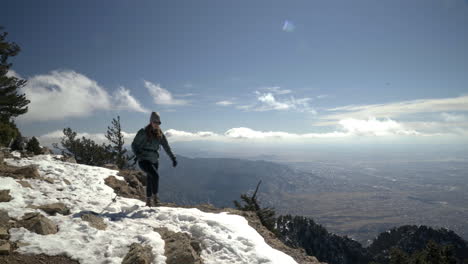 Female-hiker-walks-along-cliffside-overlooking-Albuquerque-New-Mexico,-4K