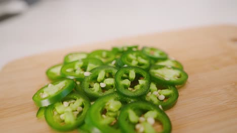 Slow-motion-drift-across-bright-green-pile-of-freshly-sliced-jalapeños-on-a-cutting-board-in-the-kitchen