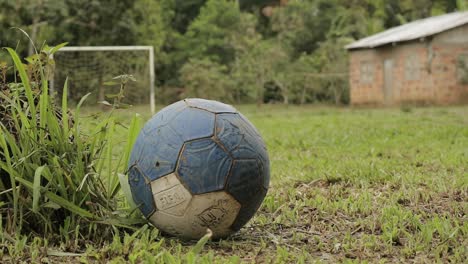 Viejo-Y-Desgastado-Balón-De-Fútbol-Abandonado-En-Medio-De-Un-Campo-Verde-En-La-Selva-Amazónica-Colombiana