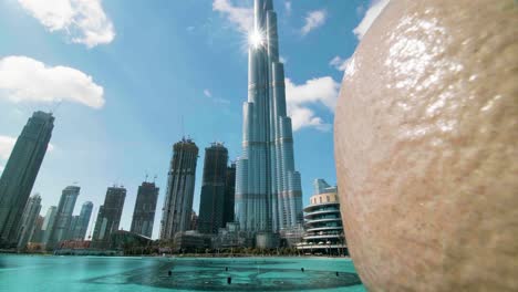 Burj-Khalifa-Con-Destello-De-Lente-Y-Nubes,-Tiro-En-Movimiento-A-La-Izquierda