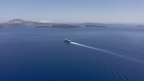 Aerial:-One-ferry-boat-sails-to-Santorini,-Greece-on-a-sunny-day