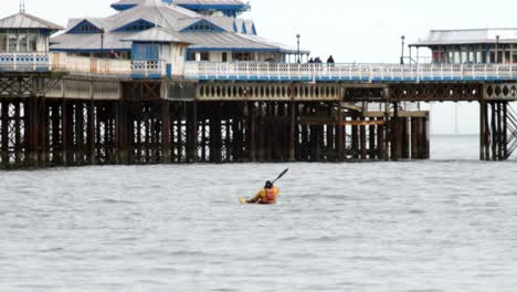 Single-lone-male-kayaking-on-wintry-sea-under-Welsh-seaside-pier