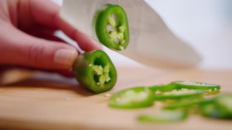 Caucasian-hand-slicing-green-jalapeño-peppers-on-cutting-board-in-slow-motion