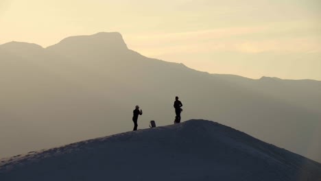 Silhouetted-tourists-take-photos-on-sand-dune-at-White-Sands-National-Park,-4K
